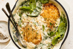 Overhead photo of Chicken Florentine with spinach in white skillet.