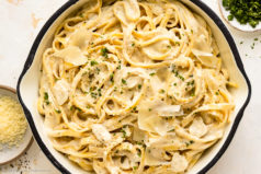 Overhead photo of cream cheese pasta with garlic and fresh herbs in a large skillet.