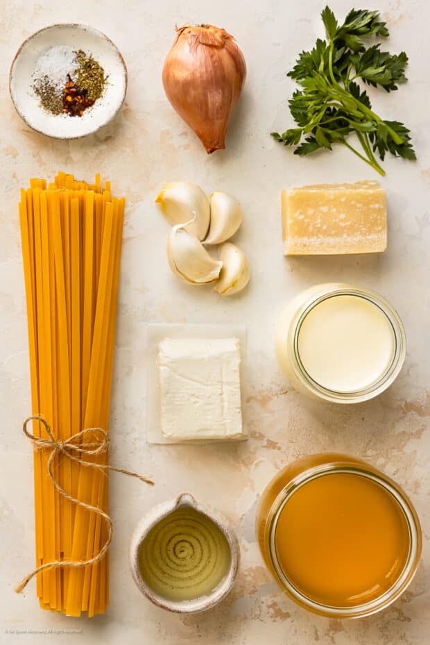 Overhead photo of the nine ingredients needed to make cream cheese pasta sauces neatly arranged on a kitchen counter.