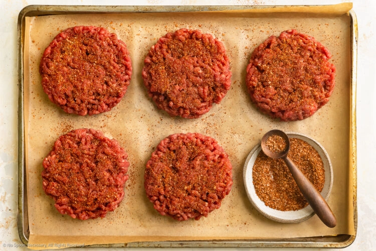 Overhead photo of five burger patties sprinkled with the best burger seasoning.