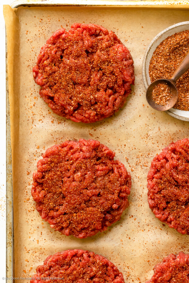 Overhead photo of burger seasonings on raw burger patties.