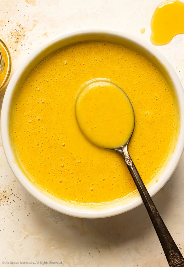 Overhead photo of honey mustard dip in a white bowl with a serving spoon.