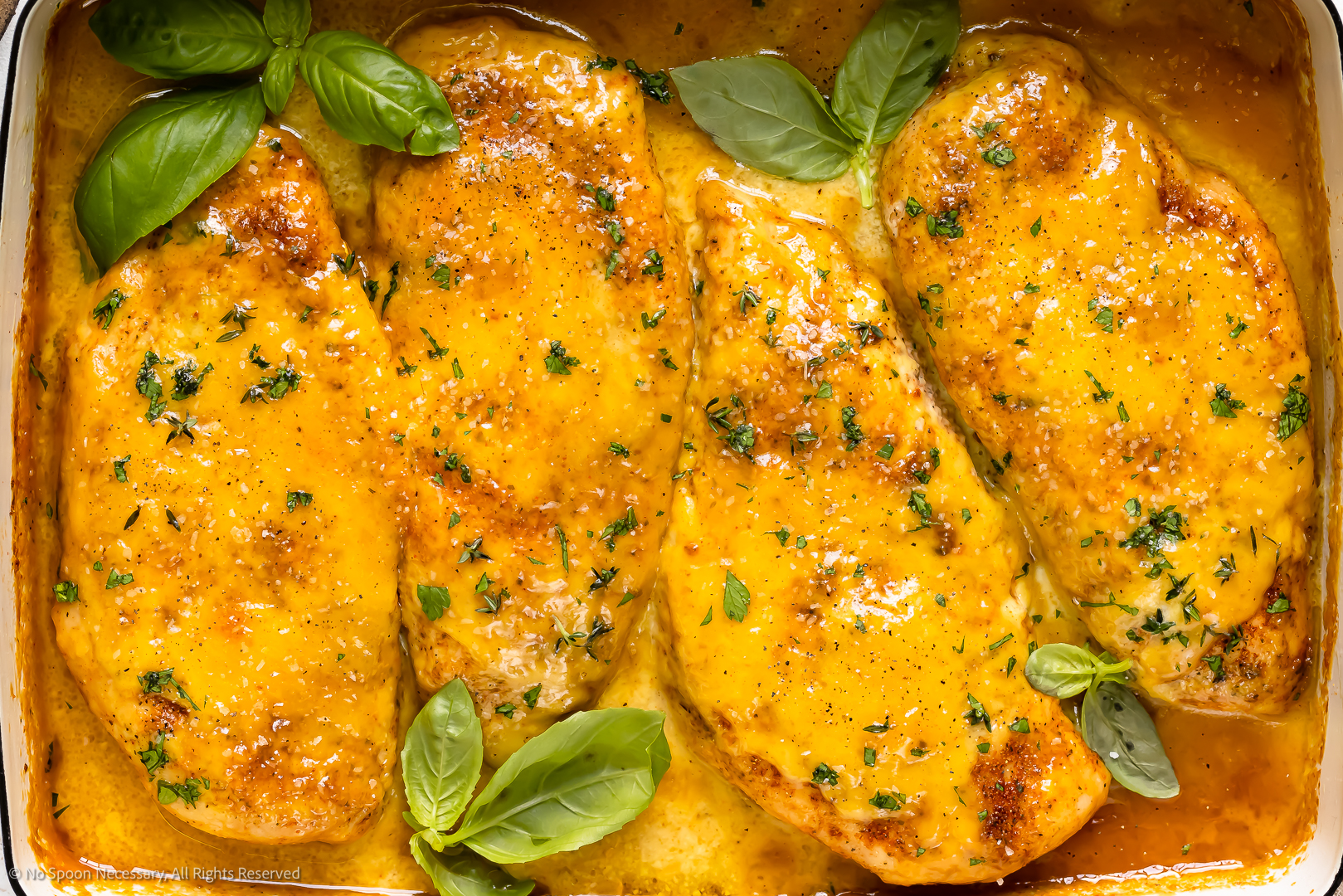 Overhead photo of four honey mustard chicken breasts in a baking dish.