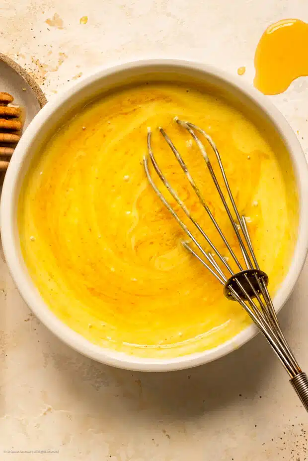 Action photo of a whisk mixing together honey mustard sauce.