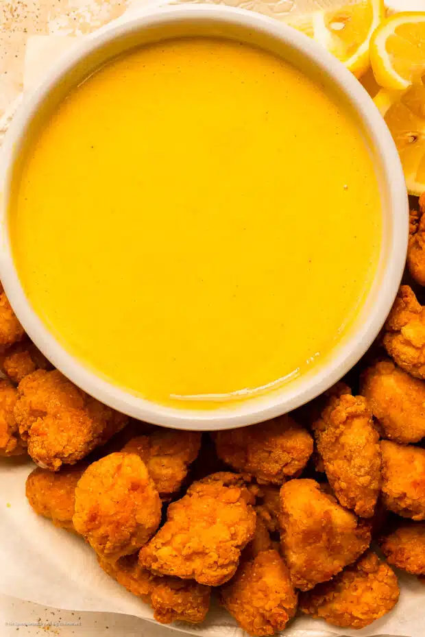 Overhead photo of a bowl of honey mustard sauce with chicken nuggets surrounding the bowl.
