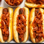 Overhead photo of three hot dogs stuffed in buns and topped with hot dog onions.