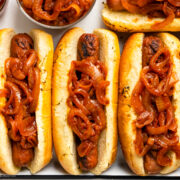 Overhead photo of three hot dogs stuffed in buns and topped with hot dog onions.