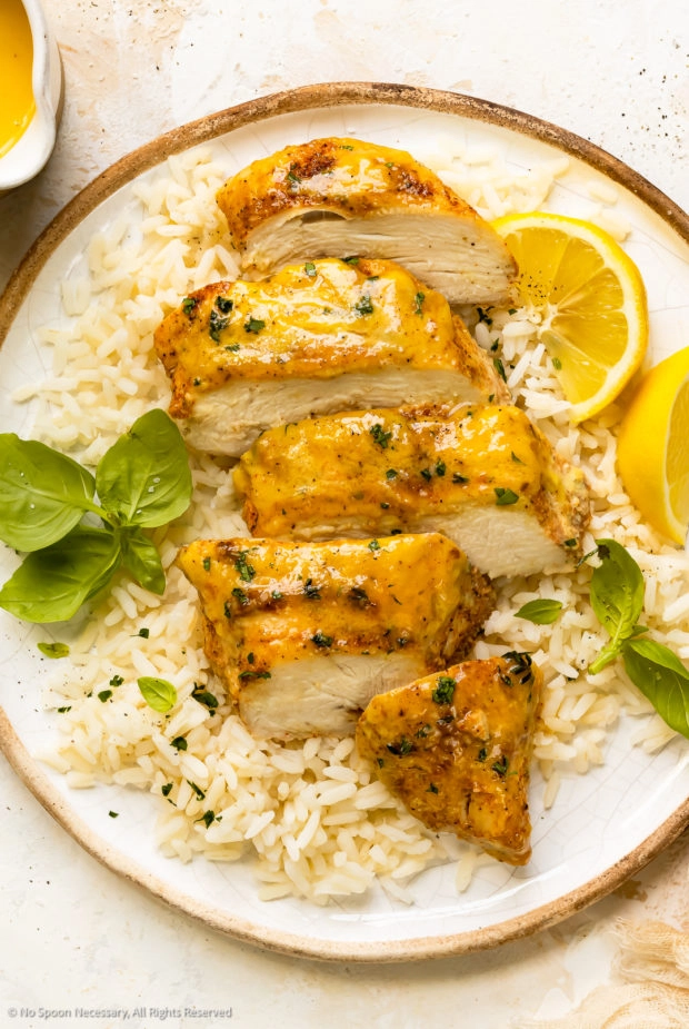 Overhead photo of a baked honey dijon chicken breast sliced into thick pieces on a bed of rice.