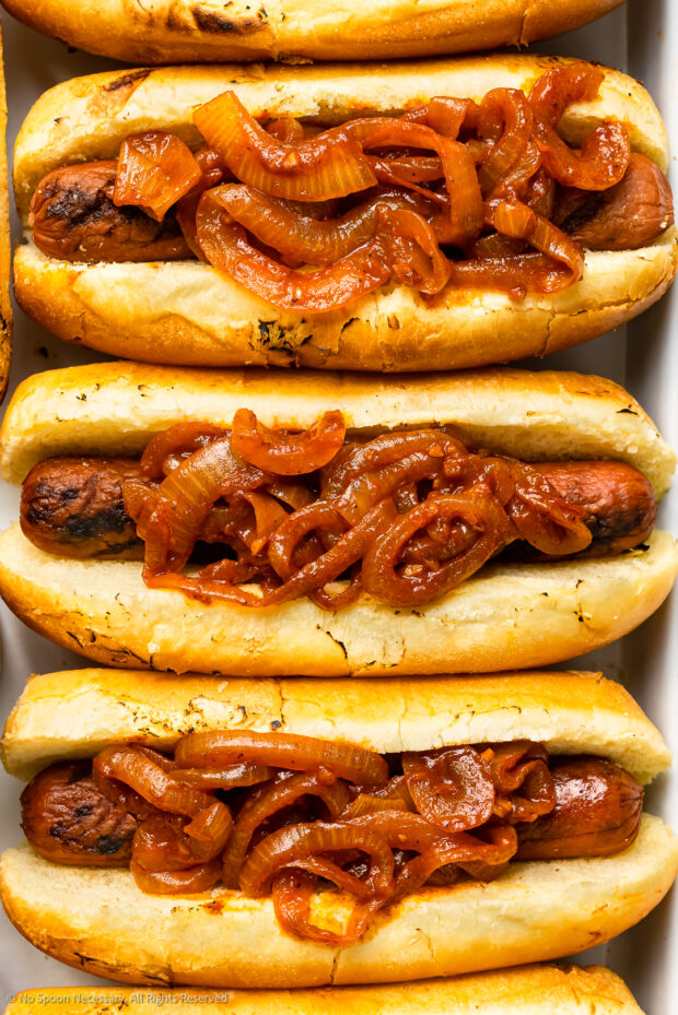 Overhead, close up photo of hot dogs topped with onion sauce.