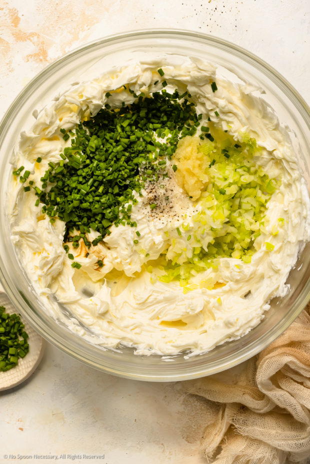 Overhead photo of whipped cream cheese topped with chive and onions in a medium mixing bowl. 