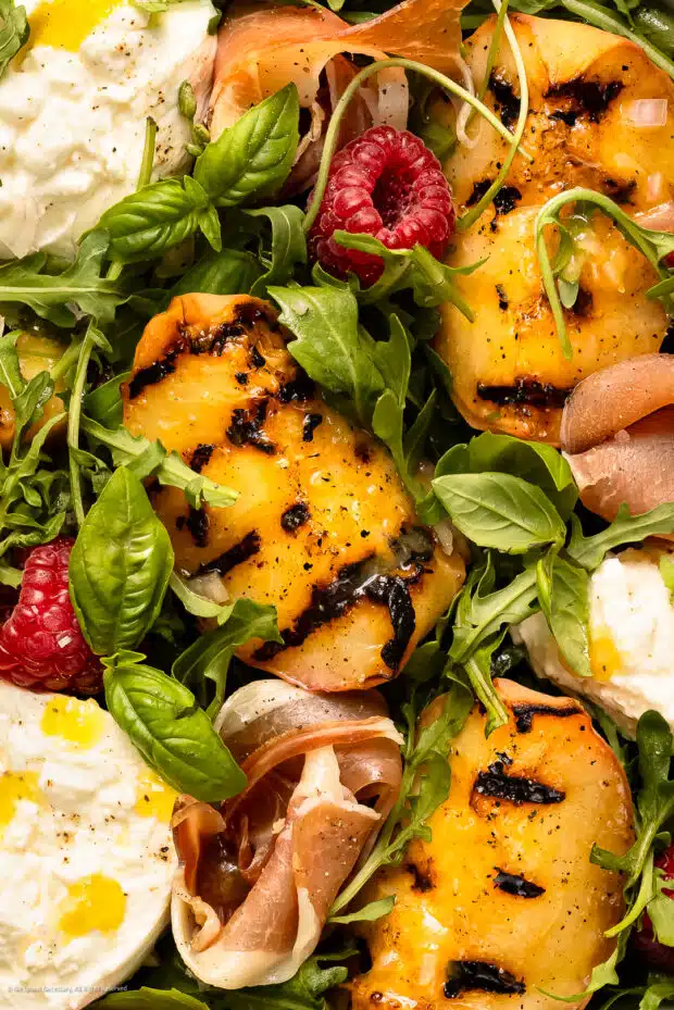 Close-up photo of torn burrata and peaches in a salad.