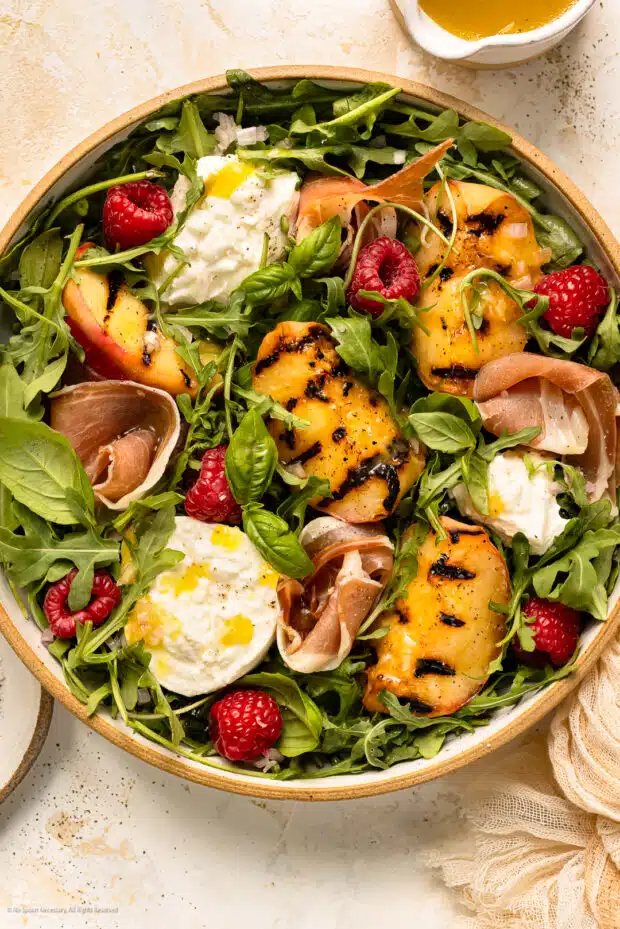 Overhead photo of dressed salad with grilled peaches and torn burrata cheese.