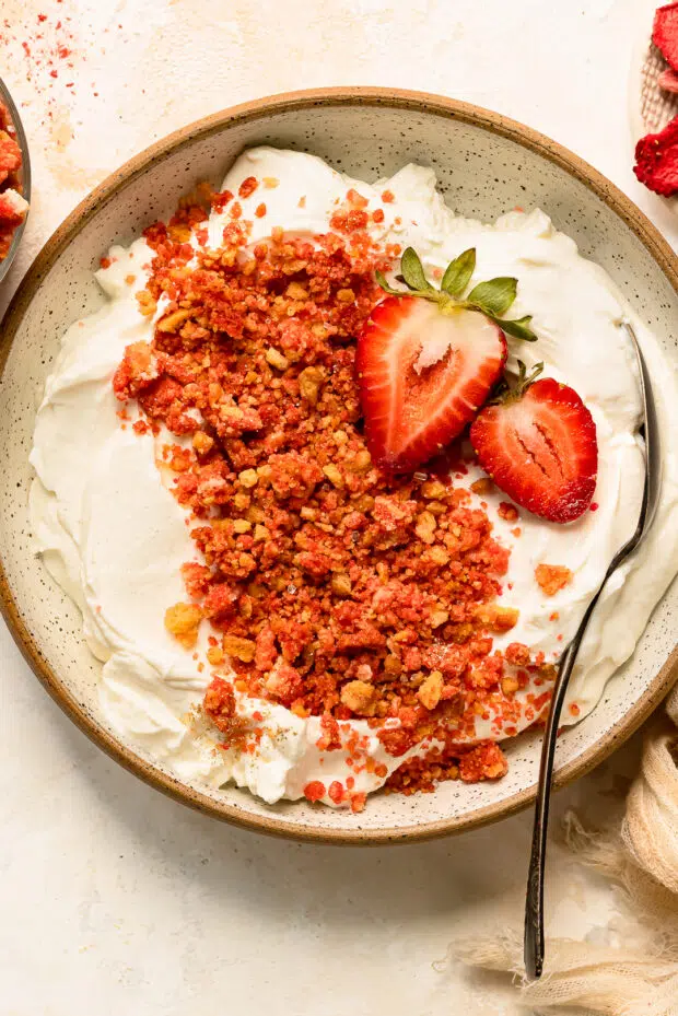 Overhead photo of strawberry shortcake topping scattered over a bowl of Greek yogurt.