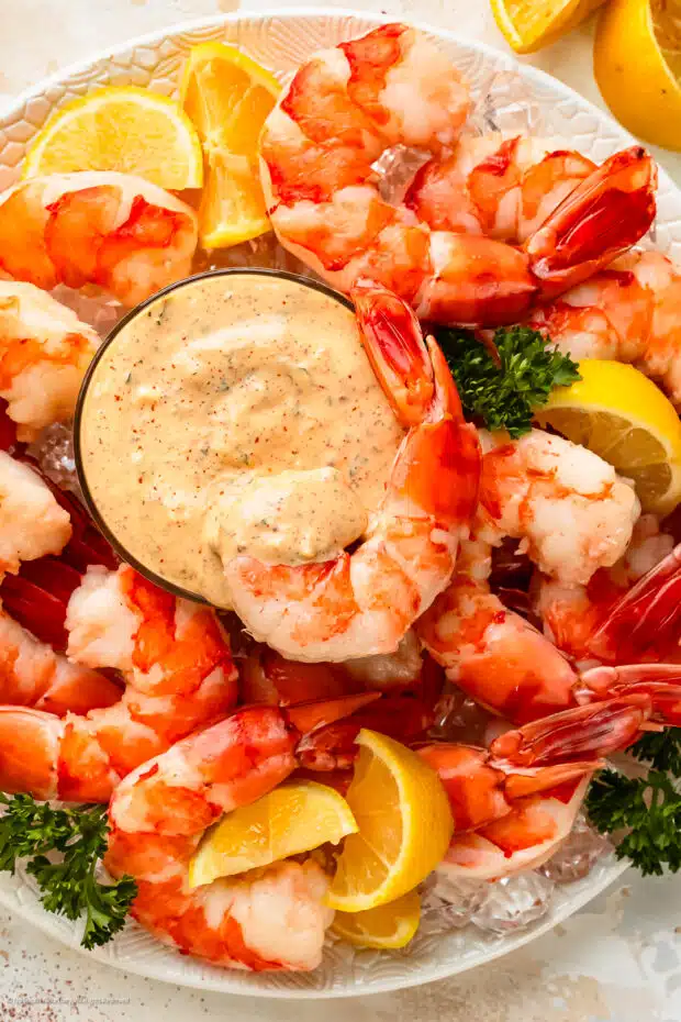 Overhead photo of a seafood platter with easy remoulade sauce, jumbo cocktail shrimp, and lemon wedges.