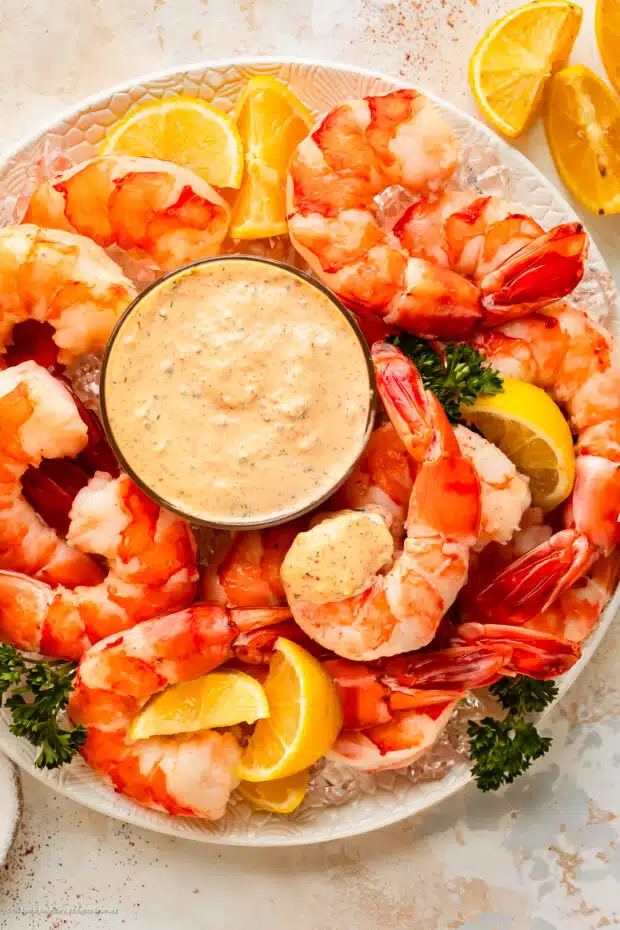 Overhead photo of a seafood platter with cajun remoulade, cocktail shrimp, lemon wedges, and parsley.