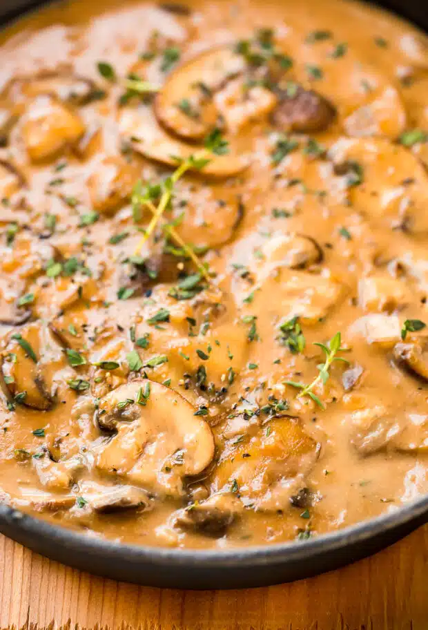 Angled, close-up photo of marsala mushrooms sauce with fresh thyme.