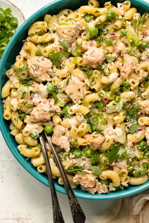 Photo of tuna macaroni salad in a blue bowl with serving spoons.