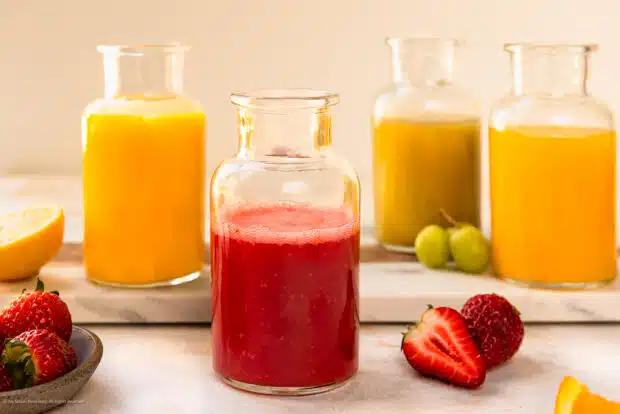 Straight on photo of four cocktail purees - strawberry, mango, orange, and grape.