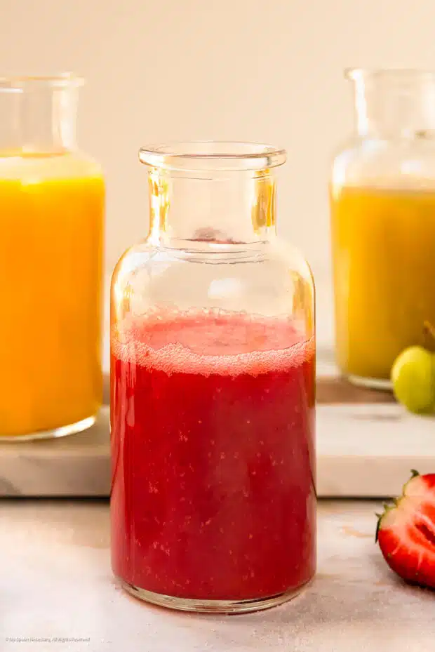 Straight on photo of a fruit puree in a glass bottle.