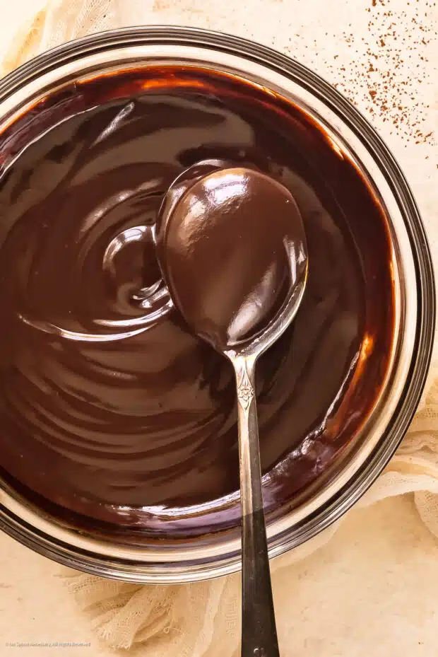 Action photo of a spoon lifting chocolate dip sauce out of a bowl.