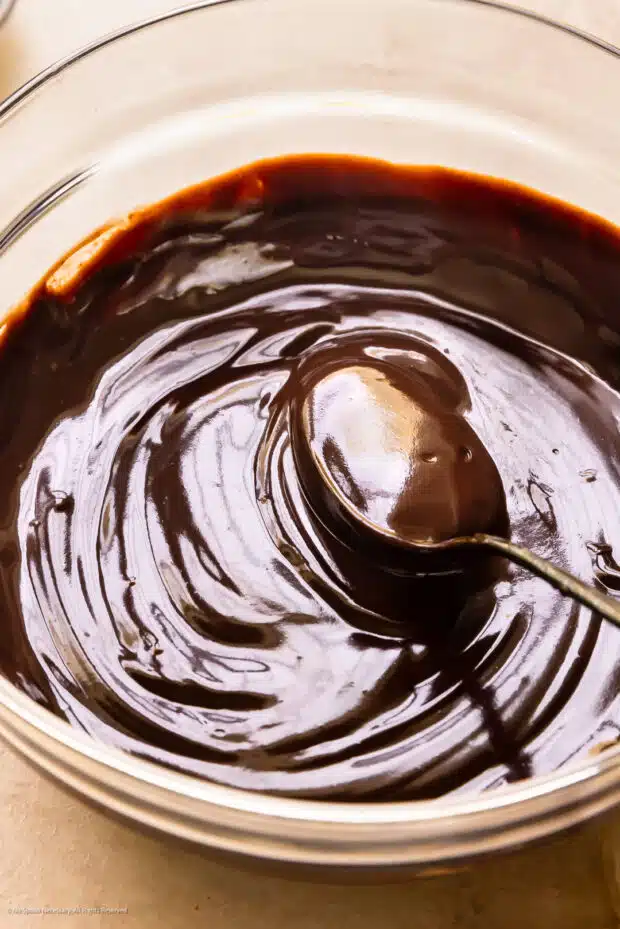 Angled photo of a spoon stirring chocolate sauce for dipping.