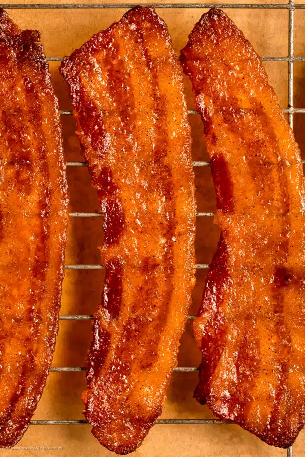 Close-up photo of two strips of candied bacon fresh from the oven.
