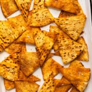 Overhead photo of crispy baked homemade pita chips on a parchment lined serving tray.