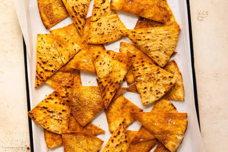 Overhead photo of crispy baked homemade pita chips on a parchment lined serving tray.