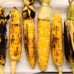 Overhead photo of six cobs of corn cooked on the grill three different ways.