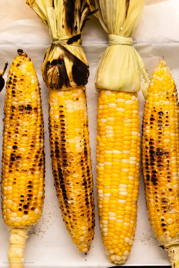 Overhead photo of four ears of grilled corn cobs.