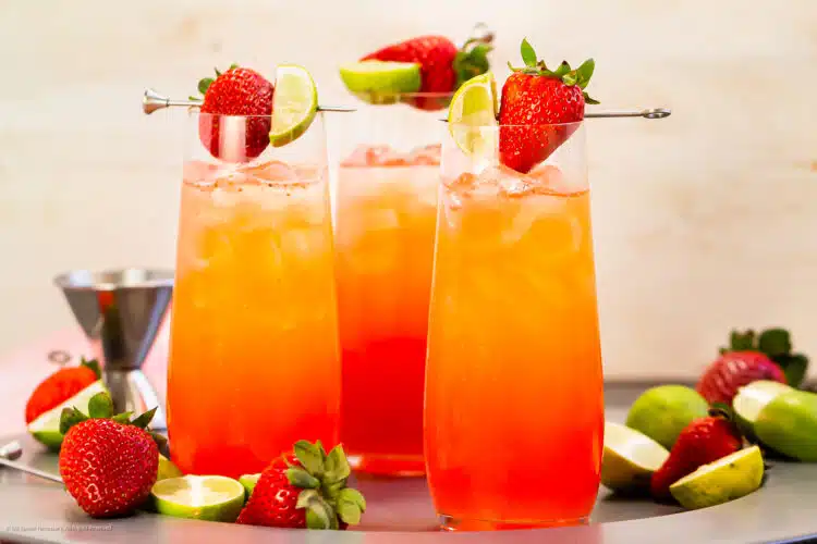 Photo of three alcoholic drinks with strawberry vodka and strawberry syrup on a serving tray.