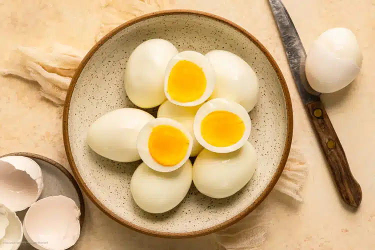 Overhead photo of six easy to peel hard boiled eggs in a bowl with the empty shells next to the bowl.