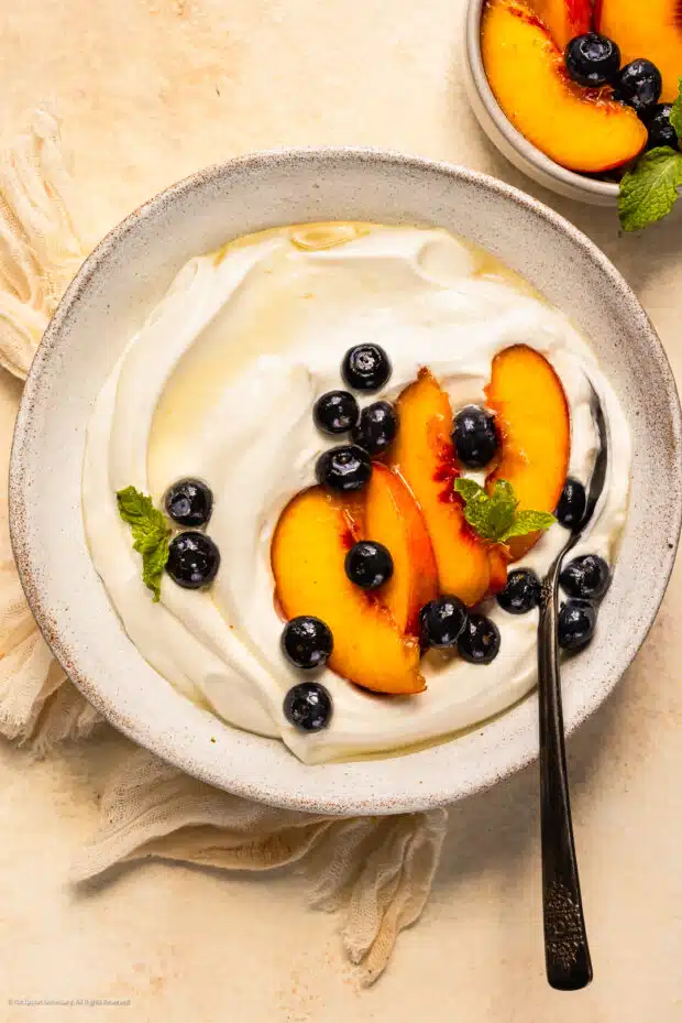 Overhead photo of Greek whipped yogurt topped with fresh fruits and a drizzle of honey.