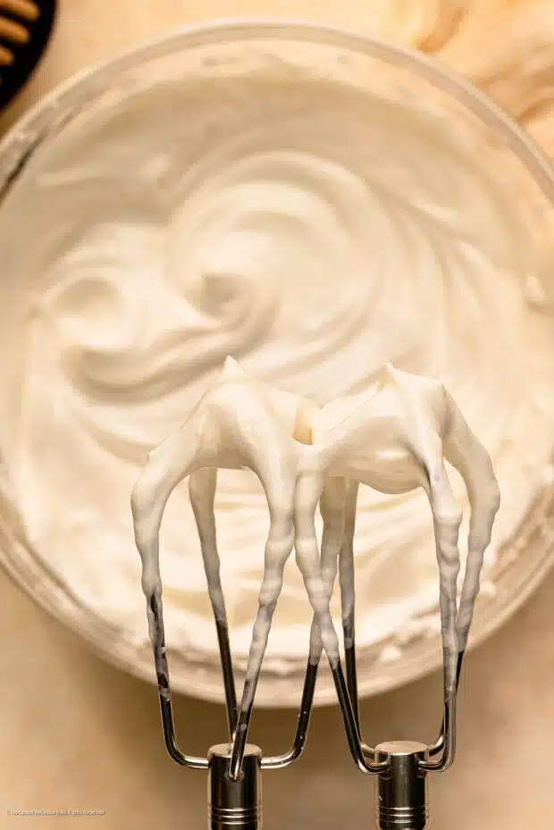 Overhead photo of a handheld beater whipping Greek yogurt.