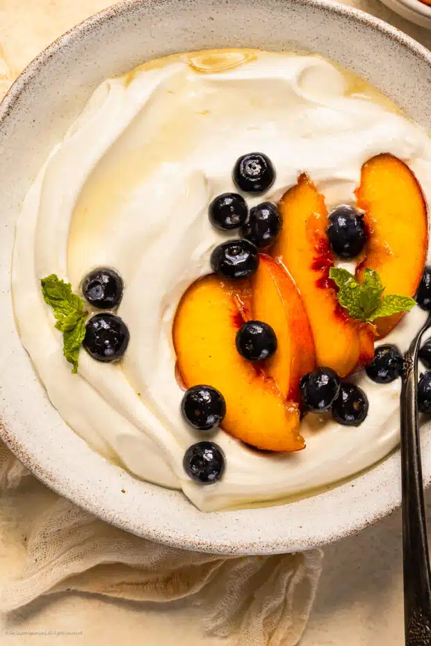 Close-up photo of a bowl of yogurt whipped cream topped with macerated fruits.