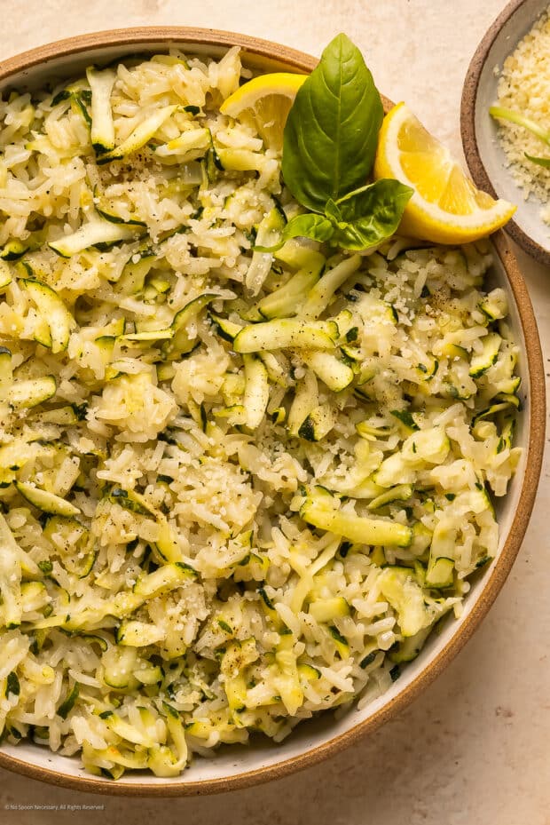 Overhead photo of cooked rice with zucchini and parmesan cheese in a serving bowl.