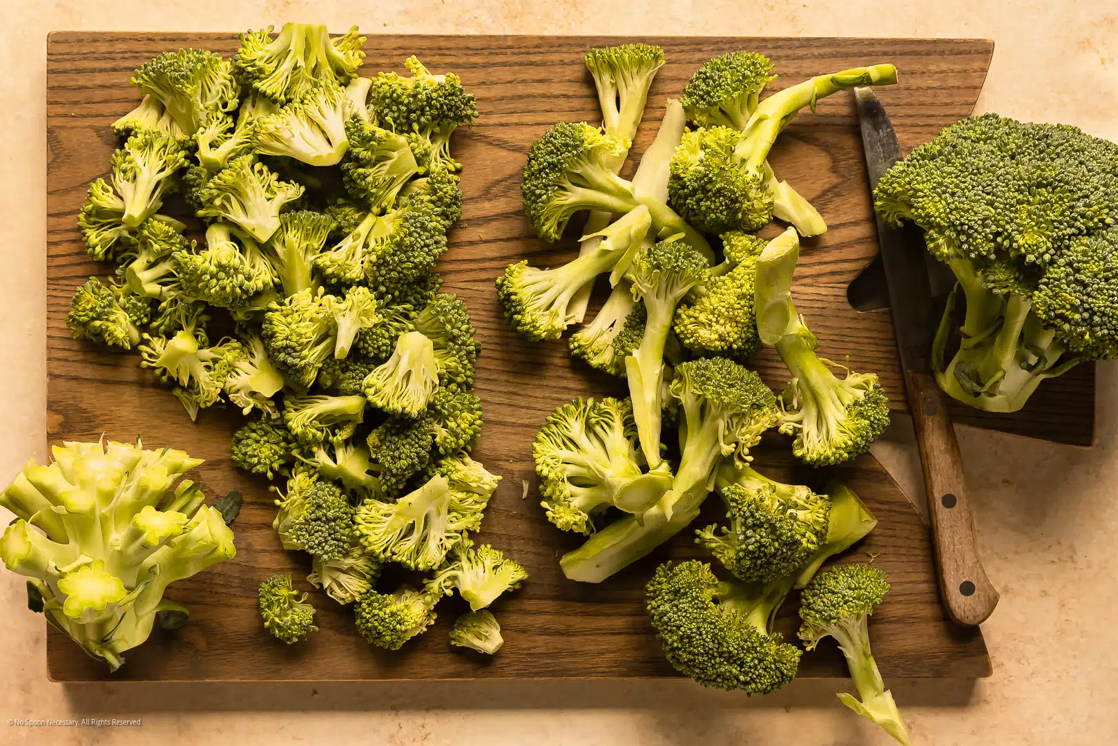 Overhead photo of two piles of cut broccoli florets - one pile with long stems and one pile with short stems.