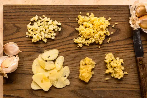 Overhead photo illustrating how to cut garlic five different ways - sliced, chopped, minced, grated, and as a paste.