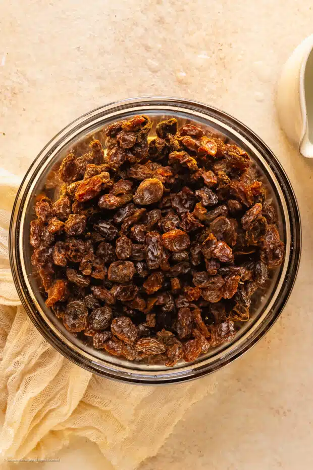 Overhead photo of dried raisins rehydrating in a bowl of warm water.