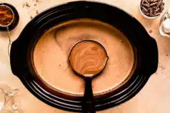 Action photo of a person ladling hot chocolate from a slow cooker.