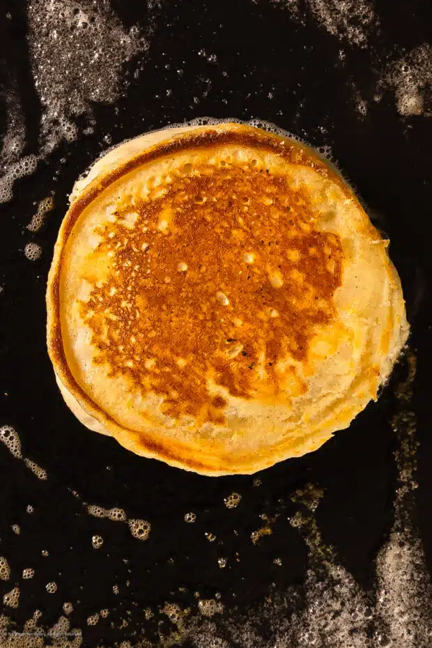 Action photo of ricotta cheese pancake cooking on a hot electric griddle.