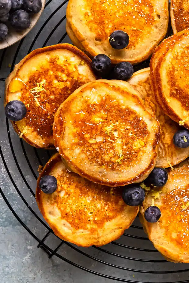 Close-up photo of a ricotta cheese pancake garnished with fresh lemon zest and a couple fresh blueberries.
