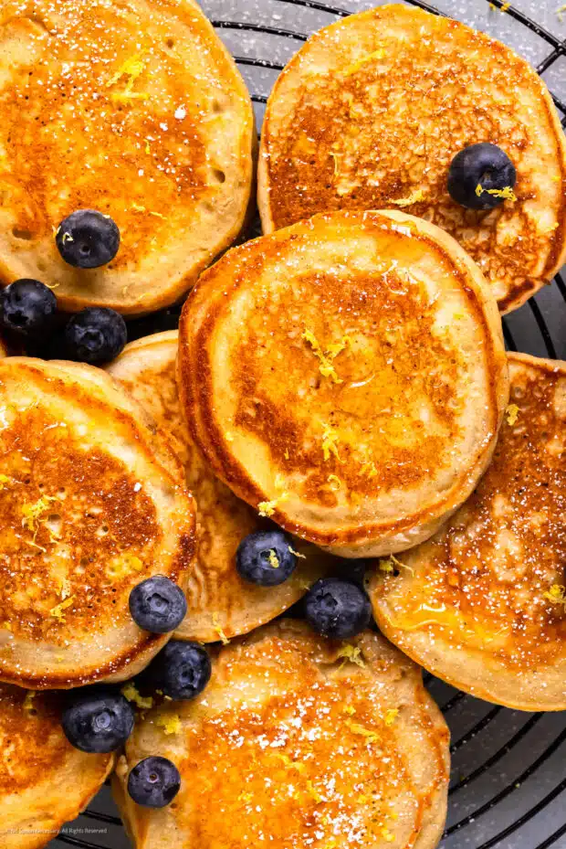 Up-close photo of a fluffy ricotta pancake surrounded by more pancakes.