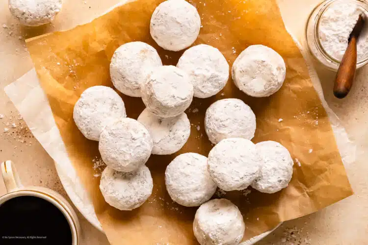 Overhead photo of mini powdered donuts on a serving tray with a cup of coffee off to the side.