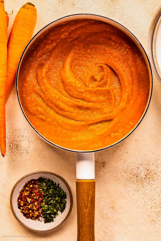 Overhead photo of a saucepan with carrots and ginger soup.