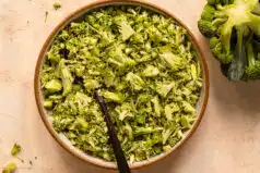 Overhead photo of riced broccoli in a serving bowl with a head of broccoli next to the bowl.