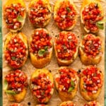 Overhead photo of bruschetta with balsamic vinegar served on crostini toasts and garnished with fresh basil.