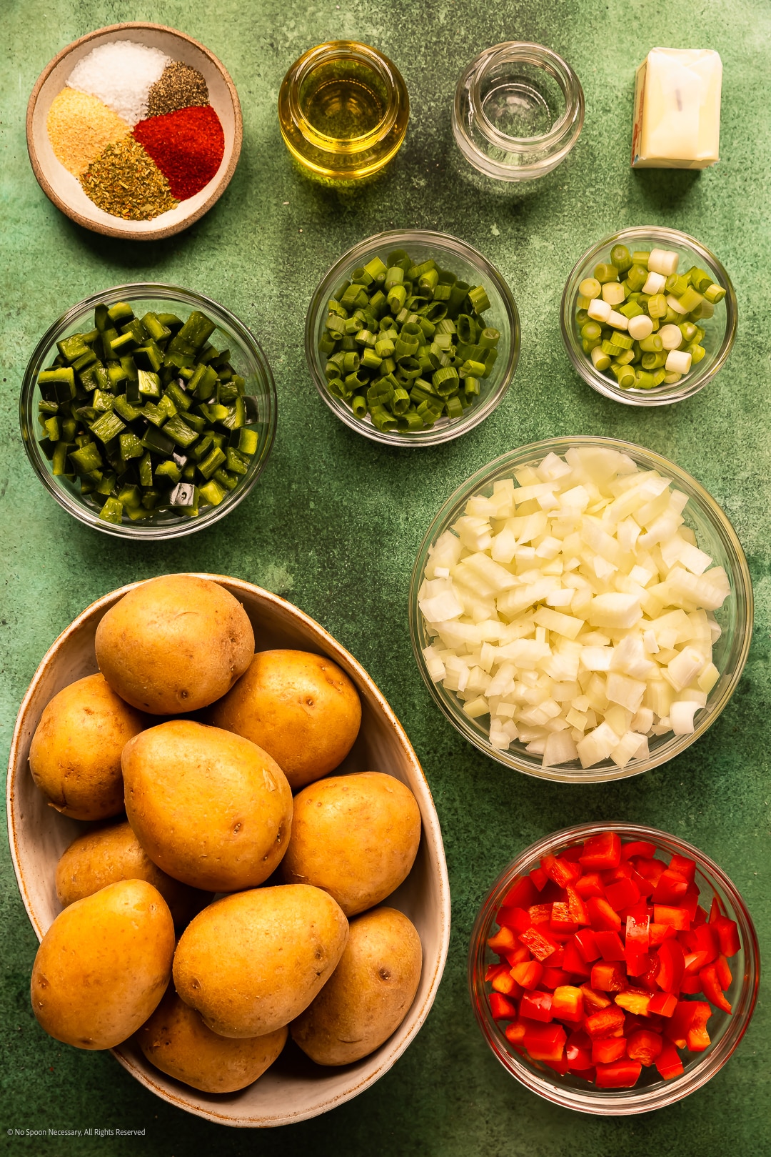 Overhead photo of yukon gold potatoes, diced onions, diced peppers, spices, and butter neatly arranged on a kitchen counter.