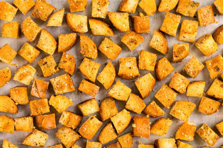 Overhead photo of homemade croutons on a large baking sheet.