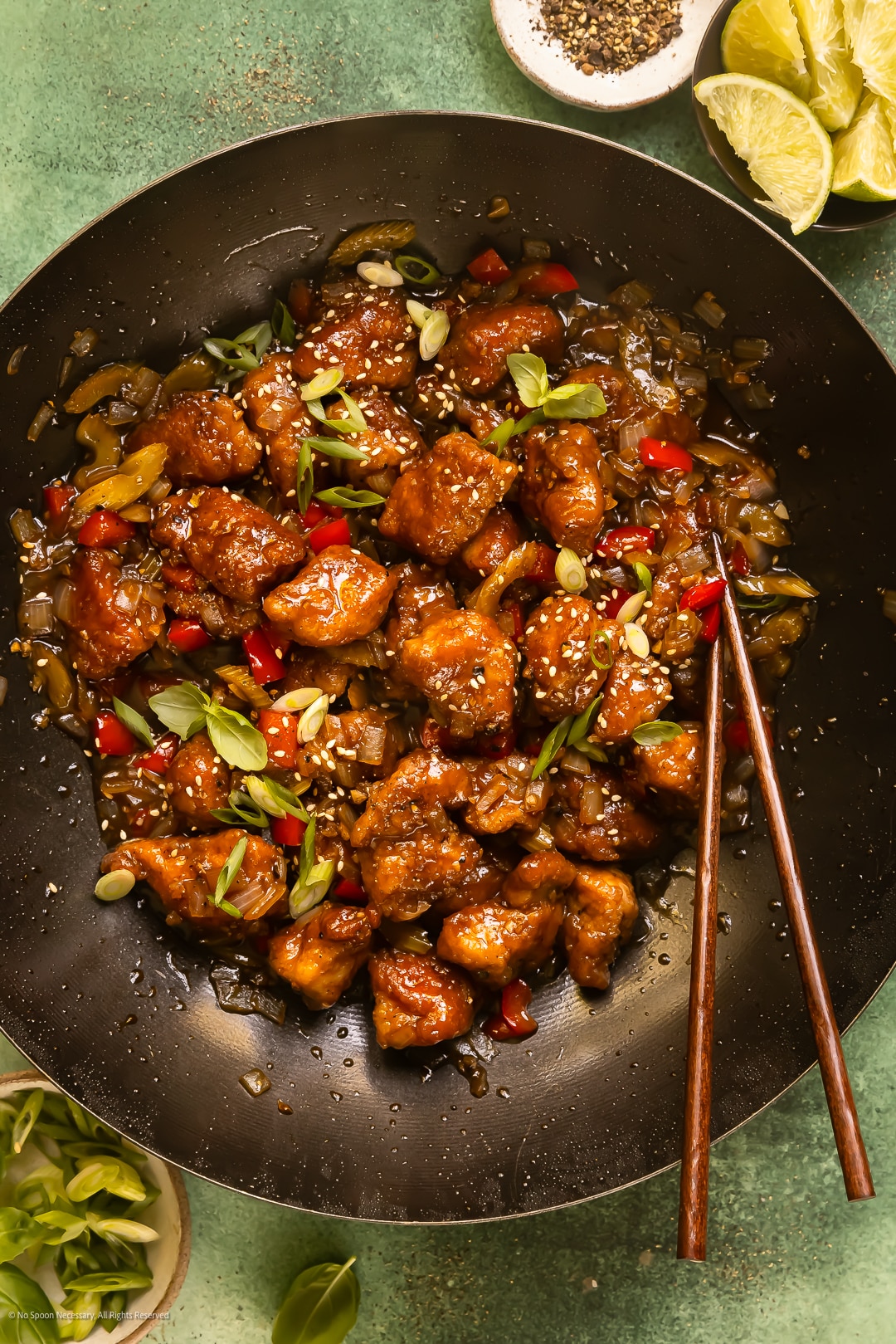 Overhead photo of stir-fried peppered chicken with veggies in a black wok.